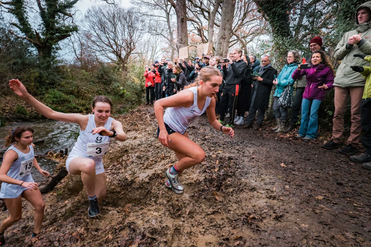Ladies’ race runners climbing out of the water splash as spectators watch, 2025