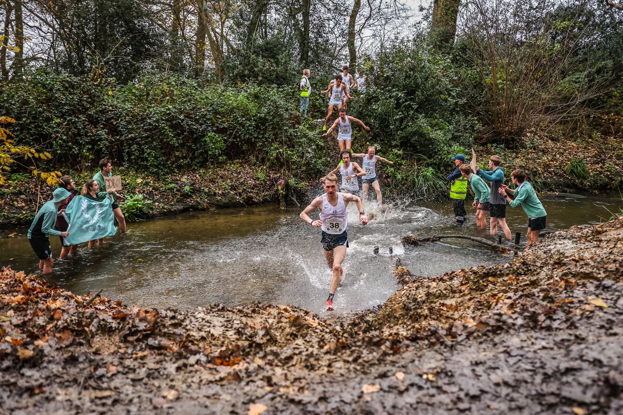 A Gentlemen’s runner wading through the water splash while others come down the bank behind
