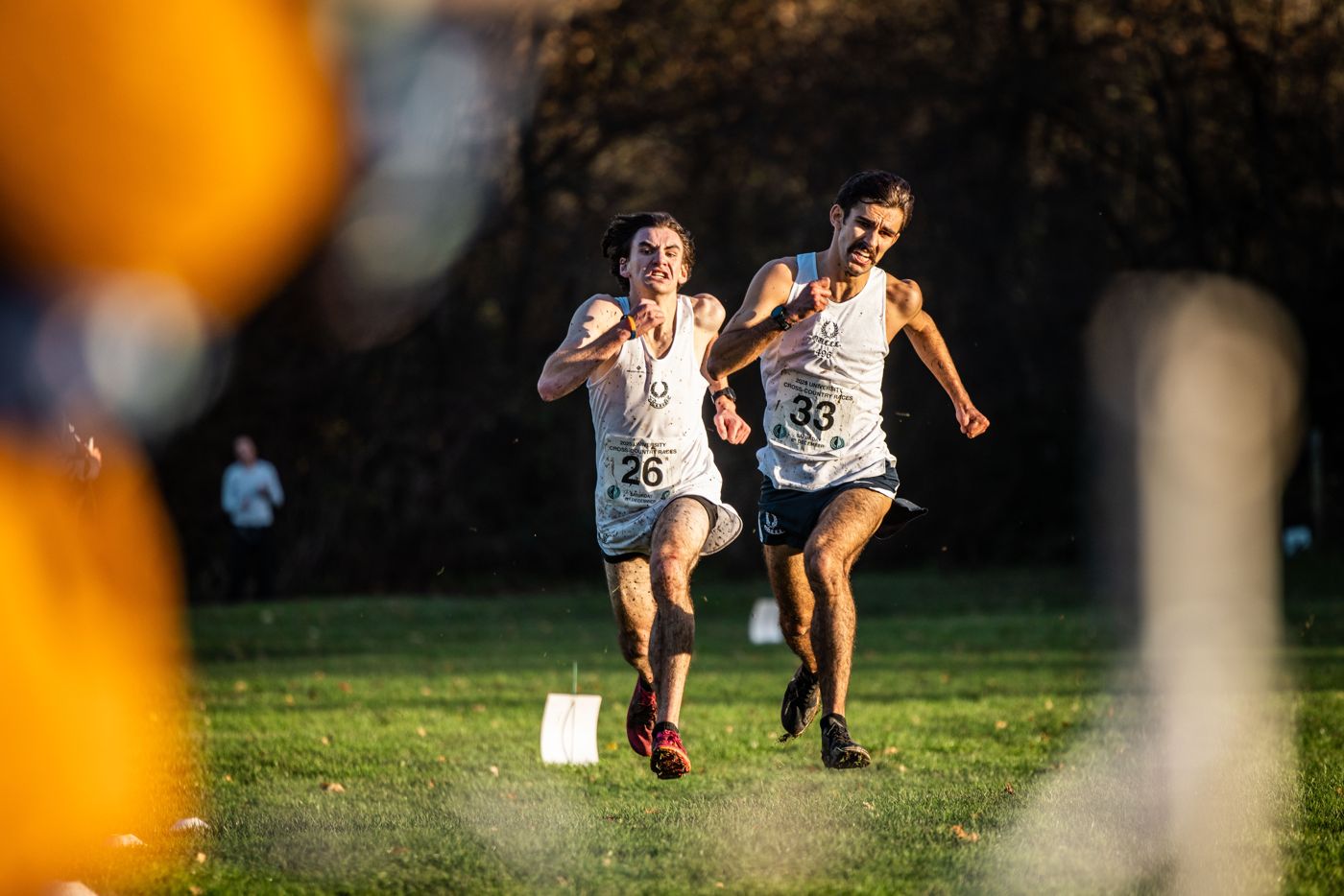 Two runners sprint side by side across the grass towards the finish.